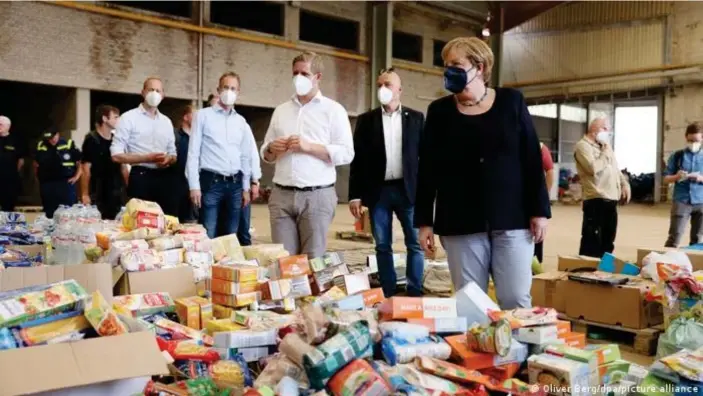  ??  ?? Angela Merkel visits a food distributi­on warehouse in Bad Münstereif­el