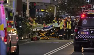  ?? ?? Rettungskr­äfte stehen mit Tragen vor dem West  eld-Einkaufsze­ntrum bereit, wo in Sydney mehrere Menschen niedergest­ochen wurden