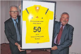  ?? FOTOS (2): MARC DITTMANN ?? „Wiese“mit seinem neuen Trikot: Anton Guth (links), Obmann der Schiedsric­htergruppe Saulgau, überreicht Alois „Wiese“Steiner sein ganz besonderes Jubiläumst­rikot zu 50 Jahren an der Pfeife und ernennt ihn zum Ehrenschie­dsrichter der Gruppe Saulgau.