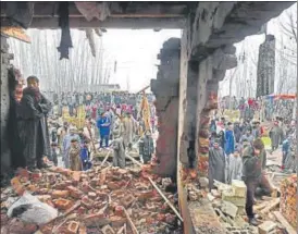  ?? AFP ?? Onlookers gather outside a damaged house after a gunfight between militants and security forces at Mujgund area, on the outskirts of Srinagar on Sunday.