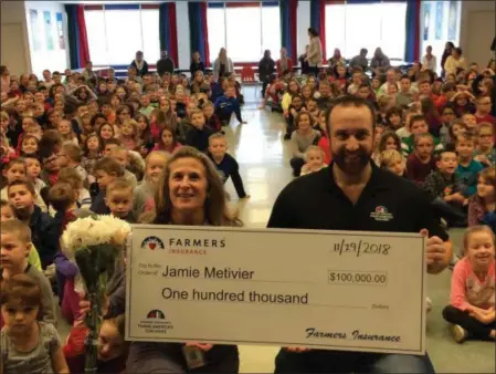  ?? PHOTOS BY PAUL POST- DIGITAL FIRST MEDIA ?? Tanglewood Elementary School teacher Jamie Metivier, left, shows off the $100,000 check she won with help from Farmers Insurance agent Jason Rickson of Ballston Spa, during a school assembly on Thursday.