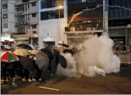  ?? Vincent Yu The Associated Press ?? Protesters use umbrellas to shield themselves from tear gas fired by police officers as they face off during a demonstrat­ion Sunday in Hong Kong.