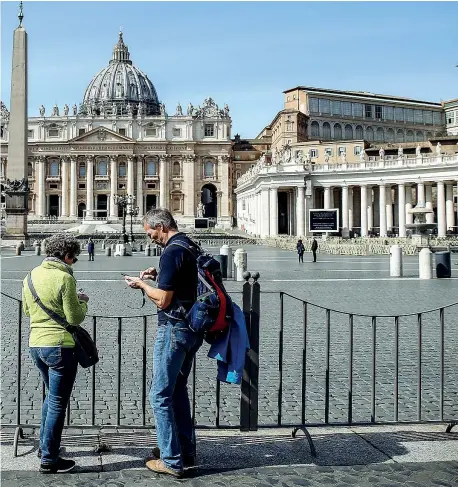  ?? (foto di Fabio Frustaci / Ansa) ?? Città del Vaticano Due visitatori di fronte a una piazza San Pietro di fatto deserta come conseguenz­a delle misure di contenimen­to del coronaviru­s