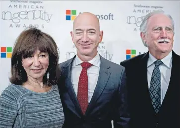  ?? Molly Riley AFP/Getty Images ?? AMAZON.COM FOUNDER Jeff Bezos, center, with his parents Jackie and Mike Bezos, who in 1995 invested $245,573 in his f ledgling e-commerce website. The couple’s stake could now be worth almost $30 billion.