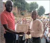  ??  ?? Mondli Zwane hands over a certificat­e to a pupil at assembly at the Kasturba Gandhi School in Inanda for participat­ion in the non-violence skills training programme.