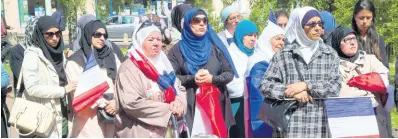  ?? AP ?? In this May 16, 2014 file photo, women wear muslim scarves and hold French flags gather outside the town hall of Mantes la Ville, northwest of Paris. The French Senate approved a bill Tuesday proposed by the mainstream right that would oblige women wearing headscarve­s to remove them when accompanyi­ng school outings.