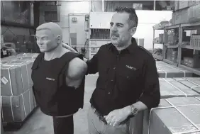  ?? CARLOS OSORIO/ASSOCIATED PRESS ?? Tom Nardone, owner of PriveCo, which sells bulletproo­f vests, is shown in his warehouse in Troy, Mich., with a mannequin wearing a test vest. In more than a hundred videos he’s posted on YouTube, Nardone takes aim at racks of ribs, laptop computers and...