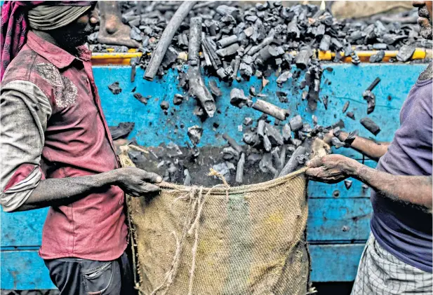  ??  ?? At the coalface Workers at a wholesale market in Mumbai, India, unload a truck of charcoal. The country, the thirdbigge­st emitter of greenhouse gases, relies on coal for two-thirds of its electricit­y but has ambitious plans to use more renewable energy sources by 2030.