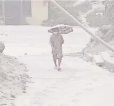  ?? — AFP photo ?? A resident of Chateaubel­air, Saint Vincent, walks on a street after the April 9 eruption of the La Soufriere Volcano.