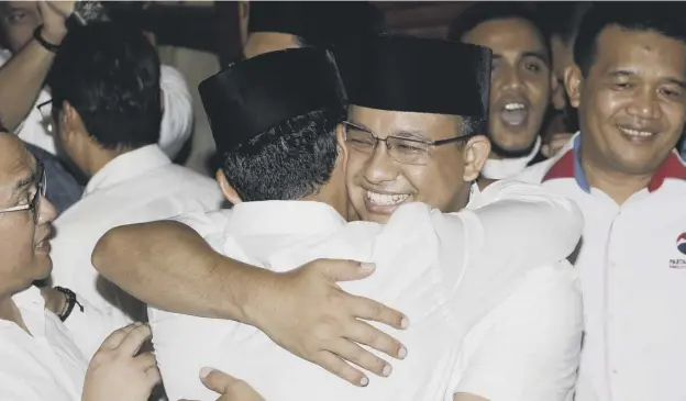  ?? PICTURE: TATAN SYUFLANA/AP ?? 0 Anies Baswedan, centre right, hugs his running mate Sandiaga Uno after early reports showed he had won election as governor of Jakarta