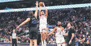  ?? — AFP photo ?? Booker (centre) shoots as Maxi Kleber (left) of the Dallas Mavericks defends during the first half at American Airlines Centre in Dallas, Texas.