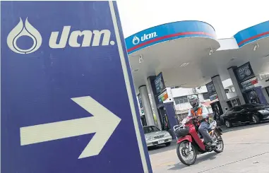  ??  ?? A motorcycli­st leaves a PTT petrol station on Sutthisan Road. More than 200 petrol stations will be transferre­d to PTTOR.