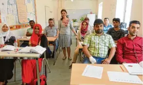  ??  ?? Lehrerin Münevver Yilmaz Kaczerowsk­i (stehend) bringt ihren Schülern im Berufliche­n Fortbildun­gszen trum die ersten deutschen Sätze bei.
