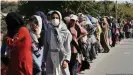  ??  ?? En Lesbos, personas solicitant­es de asilo hacen fila para recibir alimentos.