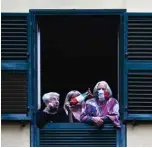  ??  ?? People with protective masks look from their windows at artists performing in the courtyard of a popular apartment building for the show Sotto lo Stesso Cielo tour (Under the Same Sky tour).