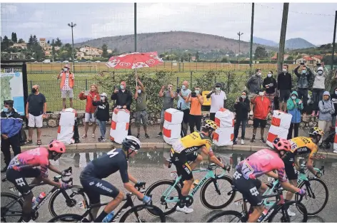  ?? FOTO: DANIEL COLE/AP ?? Fans stehen am Straßenran­d und jubeln den Fahrern bei der Tour de France zu. Die Zuschauer sind angehalten, Masken zu tragen.
