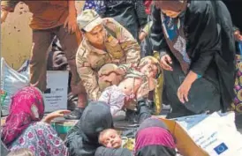  ?? AFP ?? A member of the Iraqi forces carries a child, as women who fled the fighting with Islamic State in the Old City of Mosul move belongings prior to being relocated from the western industrial district.