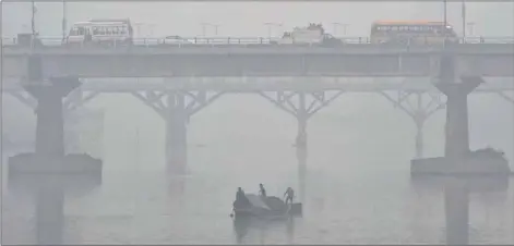  ??  ?? Kashmiri boatmen extract sand from the Jhelum river on a cold and foggy day in Srinagar yesterday.