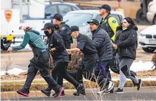  ?? CHET STRANGE GETTY IMAGES ?? Shoppers and workers are evacuated from a King Soopers grocery store in Boulder, Colo., after a gunman opened fire inside the supermarke­t. A police officer was among those who were killed.