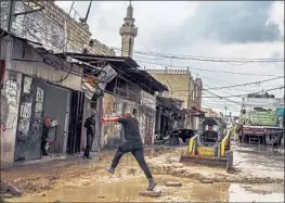  ?? Marcus Yam Los Angeles Times ?? A MAN tries to jump across a muddy street a day after Israeli forces conducted a raid last month in Jenin, West Bank. Soldiers use bulldozers to rip up the roads.