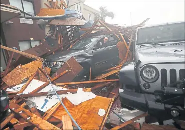  ?? GERALD HERBERT — THE ASSOCIATED PRESS ?? A storm chaser climbs into his vehicle to retrieve equipment under a collapsed hotel canopy after Hurricane Michael reached landfall in Panama City Beach, Fla., on Wednesday.