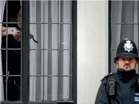  ?? PHOTO: GETTY IMAGES ?? A man takes a photograph from within the King Edward VII Hospital in London as a police officer stands guard. Prince Philip was admitted to the hospital for a routine hip operation.