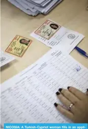  ?? —AFP ?? NICOSIA: A Turkish-Cypriot woman fills in an applicatio­n as people cast their ballot for the parliament­ary election at a polling station in the northern part of Nicosia.