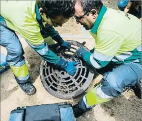  ?? XAVIER CERVERA ?? Dos técnicos retirando una tapa de alcantaril­lado para aplicar veneno