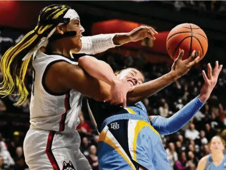  ?? Jessica Hill/Associated Press ?? UConn’s Aaliyah Edwards, left, and Marquette’s Chloe Marotta fight for a rebound during the first half in the semifinals of the Big East Tournament on Sunday.