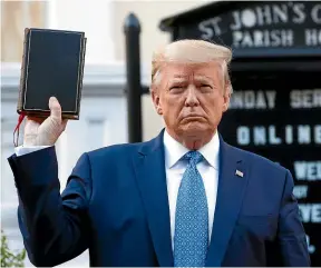  ?? AP ?? US President Donald Trump holds a Bible outside a burnt church in Washington. Instead of cooling racial flames, he has fanned them.