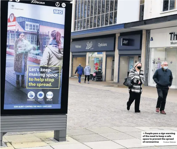  ?? Finnbarr Webster ?? People pass a sign warning of the need to keep a safe space to prevent the spread of coronaviru­s