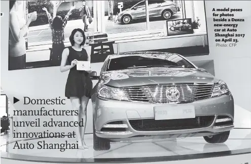  ??  ?? A model poses for photos beside a Denza new-energy car at Auto Shanghai 2017 on April 23.