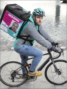  ??  ?? A Deliveroo rider is pictured with a food delivery bag showing an image of Mark Smyth, the 33 year old who was last seen in Ardee, Co Louth in 2018.