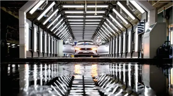  ?? XIAO YIJIU / XINHUA ?? Workers inspect a new car at the manufactur­ing facility of Dongfeng Passenger Vehicle Co in Wuhan, Hubei province.