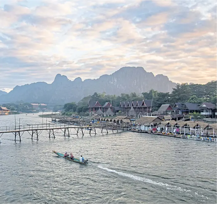  ??  ?? CALM WATERS: A bridge over the Nam Song River. Vang Vieng is a kinder, gentler version of one of Southeast Asia’s most infamous hotbeds of hedonism.