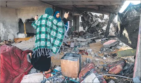  ?? ?? Women stand amid the rubble of a home destroyed by overnight Israeli bombardmen­t in Rafah in the southern Gaza Strip on Friday.