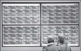  ??  ?? Men look at stock quotation boards outside a brokerage in Tokyo, Japan. REUTERS