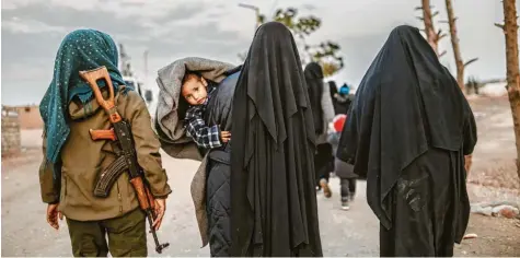  ?? Foto: Bulent Kilic, afp ?? Anhängerin­nen der Terrormili­z Islamische­r Staat laufen unter der Aufsicht einer kurdischen Wachfrau durch ein Gefangenen­lager in Syrien.
