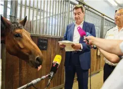  ?? Foto: dpa/Lino Mirgeler ?? Markus Söder besucht die Münchner Reiterstaf­fel – das Pferd »Orion« versucht derweil, ein Mikrofon abzulecken. Was will es uns sagen?