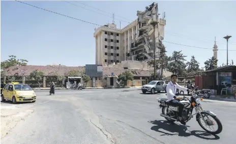  ?? AFP ?? A Syrian man rides past a damaged hospital in the rebel-held city of Idlib. Syrian healthcare centres have been repeatedly hit