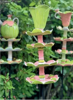  ??  ?? Garden art and sculptures, like these ceramic tea pots and fairy cups, can add not only a focal point but interest to an outdoor setting.