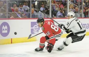  ?? ARMANDO L. SANCHEZ/CHICAGO TRIBUNE ?? Blackhawks defenseman Caleb Jones, left, and Kings center Trevor Moore chase the puck during the second period Thursday at the United Center.