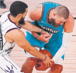  ?? KEVIN C. COX GETTY IMAGES ?? Raptor Fred VanVleet and former teammate Jonas Valanciuna­s of the Grizzlies fight for possession in Sunday’s game in the NBA bubble, where Toronto is now 4-1.