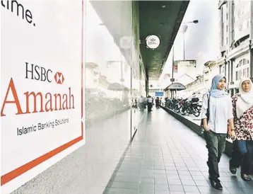  ??  ?? Consumers walking past a branch of HSBC Amanah, the Islamic finance arm of HSBC. Malaysia has the capability to help train many countries in Islamic banking products due to the country’s position as one of the key players in Islamic finance. —...