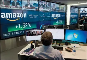  ?? AP/MARK LENNIHAN ?? A Nasdaq employee monitors market activity Tuesday at the New York Stock Exchange. Amazon flirted with a market value of $1 trillion, becoming just the second publicly traded company to reach the milestone.