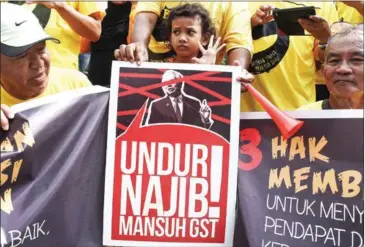  ?? MOHD RASFAN/AFP ?? A child in Malaysia’s northern town of Ipoh stands behind a placard reading ‘Please Step Down Najib’ as members of civil society alliance Bersih pose for pictures ahead of their demonstrat­ion in the capital Kuala Lumpur to demand Prime Minister Razak...