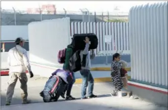  ?? GREGORY BULL — THE ASSOCIATED PRESS ?? A family leaves to apply for asylum in the United States, at the border, Friday in Tijuana, Mexico.