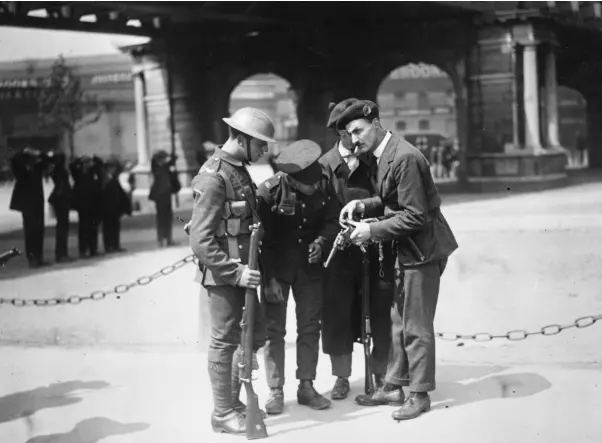  ??  ?? HISTORY: British soldiers watch a member of the Black and Tans reload his .45 revolver after the burning of the Custom House in Dublin in 1921