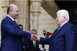  ?? (Thaier Al-Sudani/Reuters) ?? IRAQ’S OUTGOING President Fuad Masum (right) and newly elected Barham Salih shake hands at Salam Palace in Baghdad on Wednesday.