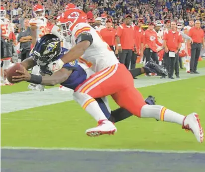  ?? KARL MERTON FERRON/STAFF ?? Ravens quarterbac­k Lamar Jackson dives into the end zone past Chiefs defensive end Mike Danna for a touchdown during the fourth quarter Sept. 19, 2021.